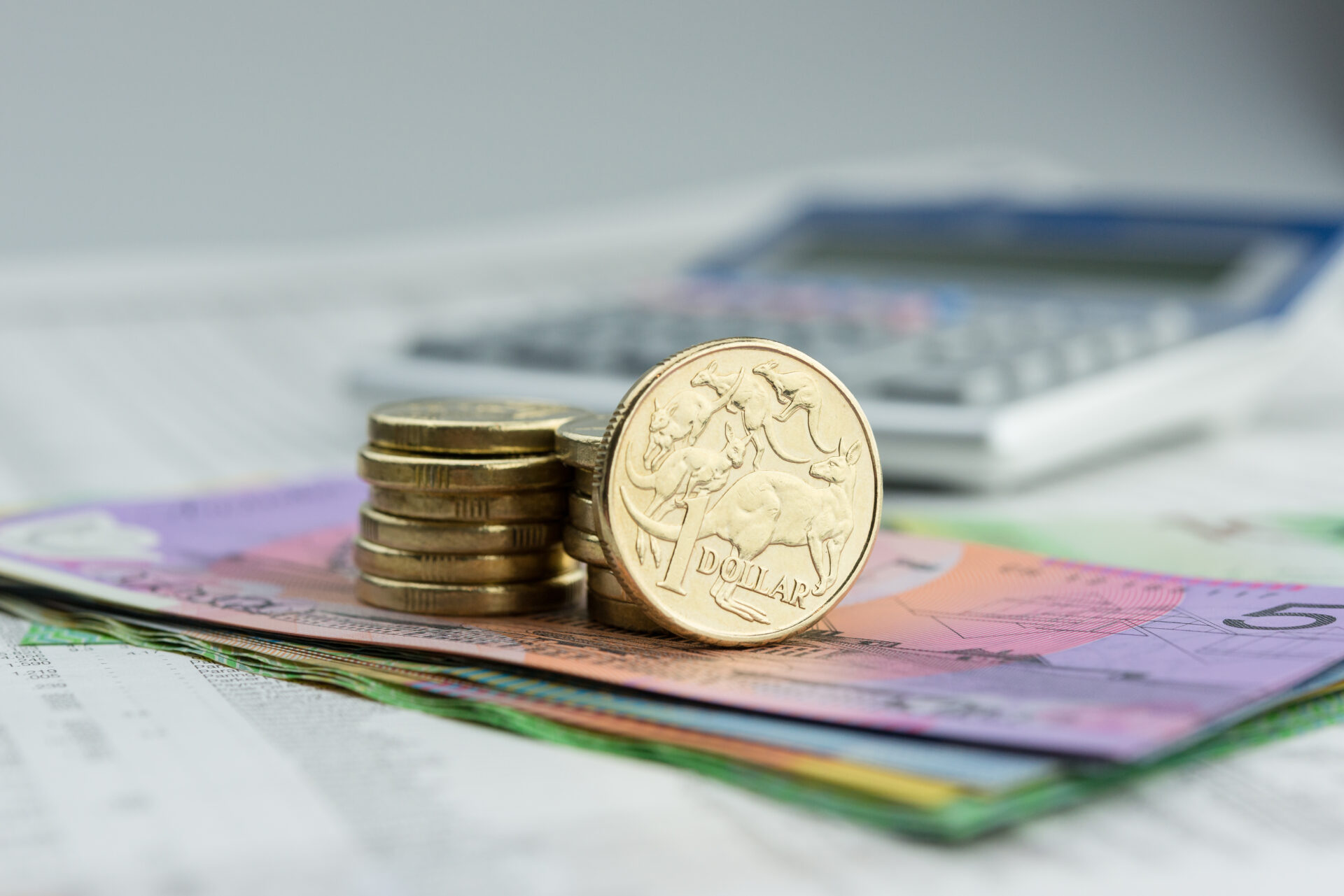 Stacks of Australian coins and notes with a calculator, symbolizing financial planning for investors navigating tax changes.